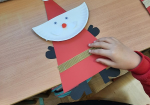Dzieci wykonują postać Mikołaja z czerwonego kartonu, papierowego białego talerzyka i innych drobnych dodatków.