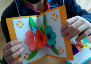 Dzieci wykonują laurki dla babci i dziadka. Kartki z okazji dnia babci i dziadka wykonane z kartonu, kwiaty wykonane z kolorowych kartek ksero. Pojedyncze kwiaty sklejone w bukiet.