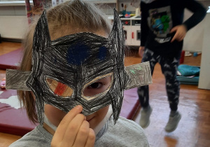 Dzieci prezentują wykonane przez siebie maski karnawałowe. Maski wydrukowane na papierze ksero były kolorowane kredkami i wycinane.