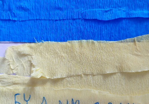 Prace wykonane z kolorowego kartonu i bibuły w barwach niebiesko- żółtych, ozdobione sercem i ciepłymi życzeniami.