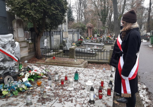 Uczniowie wraz z nauczycielem składający znicze przy symbolicznych mogiłach - pomnikach AK i Szarych Szeregów.