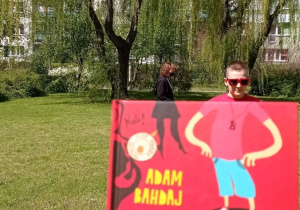 Praca Grzegorza Czyżewskiego - Zdjęcie wykonano w plenerze do książki Adama Bahdaja „Stawiam na Tolka Banana”. Na tle wierzby płaczącej widnieje chłopiec w okularach przeciwsłonecznych.