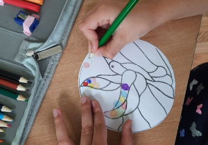 Dzieci rysują małe kolorowe kółka wypełniając nimi kontur ptaszka.