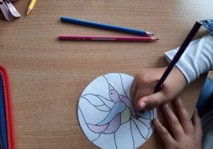 Dzieci rysują małe kolorowe kółka wypełniając nimi kontur ptaszka.