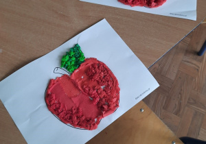 Dzieci wyklejają narysowane gruszki i jabłka kawałkami bibuły