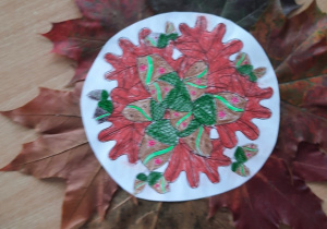 Jesienna mandala – praca plastyczna wykonana z ususzonych kolorowych liści naklejanych dookoła pod pokolorowaną mandalę.