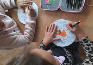 Dzieci kolorują kredkami mandalę.
