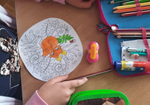 Dzieci kolorują kredkami mandalę.