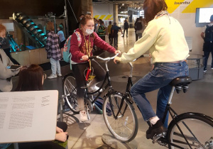 Uczennice siedzą na rowerach, które są eksponatami na "Wystawie rowerów"