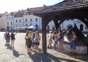 Uczniowie stojący przy zabytkowej studni na rynku w Kazimierzu Dolnym