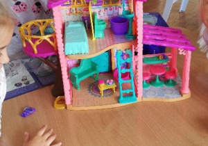 Dzieci bawiące się domkiem dla lalek.